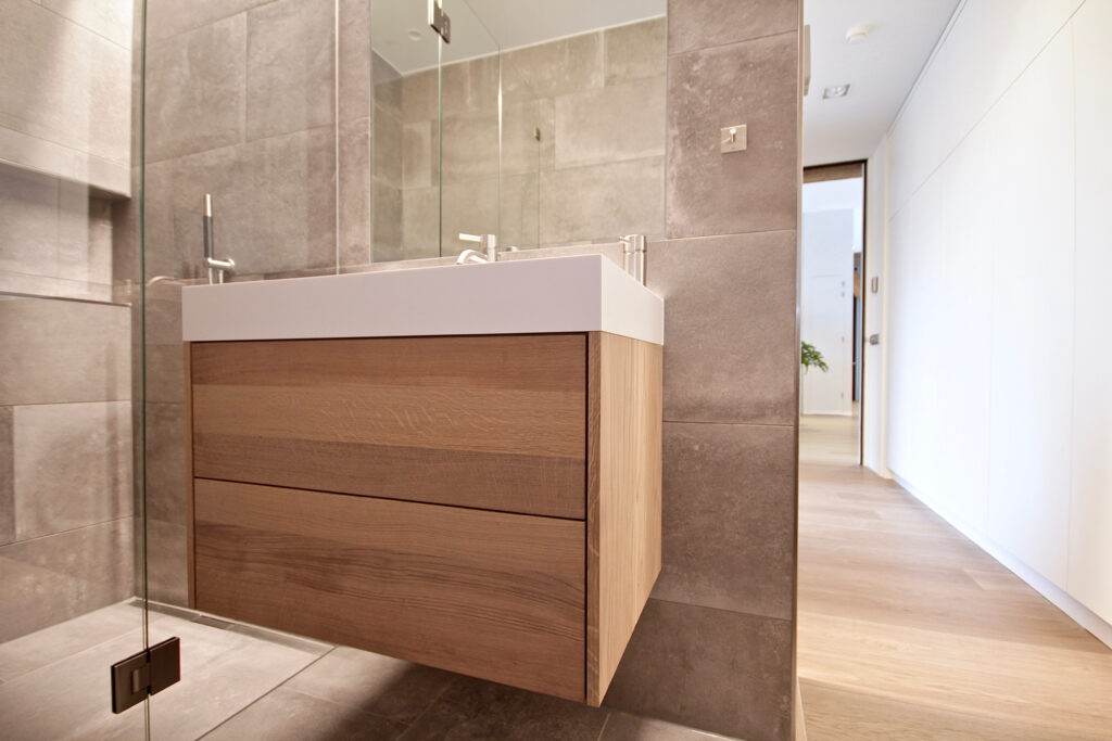 Eiken maatwerk wastafelonderkast greeploos met wit solid surface blad